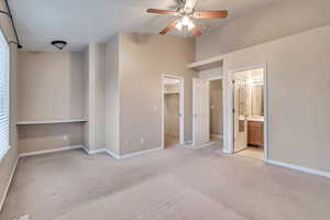 Unfurnished bedroom with light colored carpet, a walk in closet, and baseboards
