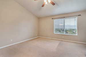 Unfurnished room featuring light carpet, baseboards, ceiling fan, and lofted ceiling