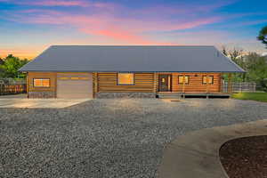 View of front of home featuring a metal roof, an oversized garage with 9' door, fence, and log siding