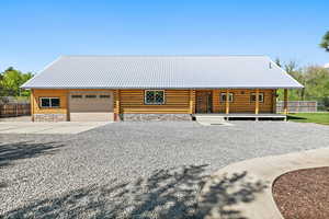 Cabin with log exterior, concrete driveway, fence, and a garage