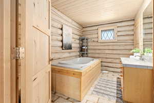 Well-designed bathroom with wood ceiling, log walls, vanity, jetted tub, and separate shower