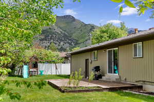 Rear view of house with a mountain view, a playground, and entry steps