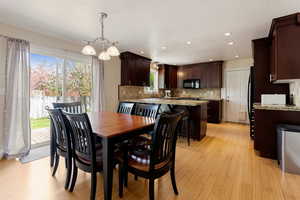 Dining room with healthy amount of natural light, light wood-style floors, recessed lighting, and a chandelier