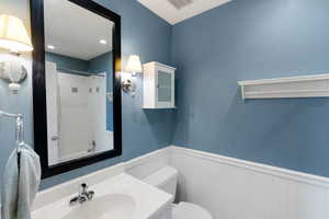 Full bathroom featuring a wainscoted wall, toilet, and vanity