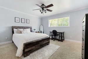 Bedroom featuring crown molding, baseboards, carpet flooring, and ceiling fan