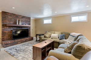 Carpeted living room with baseboards, crown molding, a fireplace, and recessed lighting