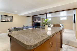 Kitchen with light carpet, open floor plan, a kitchen island, baseboards, and a brick fireplace
