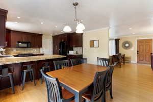 Dining space with recessed lighting, crown molding, and light wood-style floors