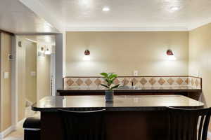 Kitchen featuring a sink, dark countertops, a kitchen breakfast bar, and crown molding