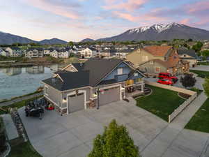 View of front of house featuring a residential view, a garage, stone siding, a water and mountain view, and driveway