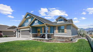 Craftsman house featuring covered porch, driveway, a mountain view, stone siding, and a garage