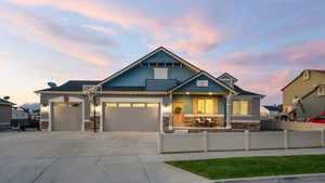 View of front of home with stone siding, a garage, and concrete driveway