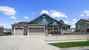 Craftsman house featuring fence, stone siding, an attached garage, and concrete driveway