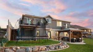 Back of house at dusk with a gazebo, a yard, stucco siding, stairway, and a patio area