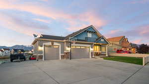 View of front of home with an attached garage, driveway, stone siding, and a mountain view