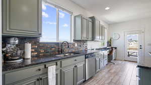 Kitchen with stainless steel dishwasher, a sink, gray cabinets, decorative backsplash, and recessed lighting