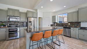 Kitchen with stainless steel appliances, light wood-type flooring, gray cabinetry, tasteful backsplash, and recessed lighting