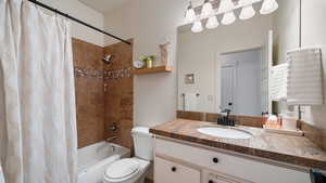 Full bath featuring shower / bathtub combination with curtain, vanity, and toilet