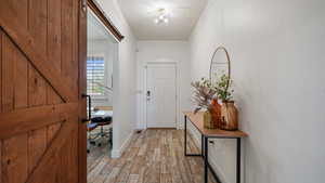 Entryway with light wood-type flooring, a barn door, and baseboards