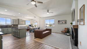 Living area featuring a ceiling fan, wood finished floors, lofted ceiling, baseboards, and a fireplace