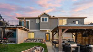 Back of property with stucco siding, a gazebo, a yard, an outdoor living space, and stairs