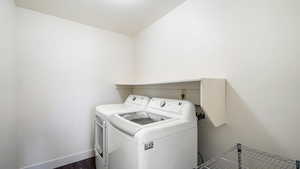 Washroom with washer and clothes dryer, dark wood-style flooring, and baseboards