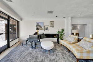 Living room featuring a textured ceiling, crown molding, and recessed lighting