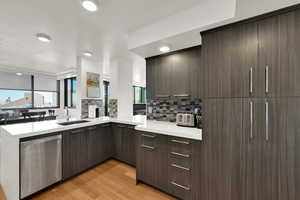 Kitchen featuring decorative backsplash, a sink, modern cabinets, and light countertops