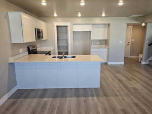 Kitchen featuring stainless steel appliances, a peninsula, baseboards, light countertops, and a sink