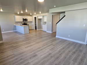 Kitchen with stainless steel appliances, open floor plan, a peninsula, baseboards, and a sink