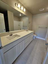Full bath featuring tile patterned flooring, toilet, double vanity, a shower, and a textured ceiling