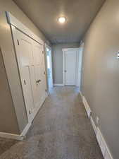 Corridor featuring carpet floors, a textured ceiling, and baseboards