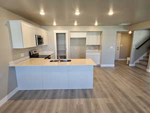 Kitchen with stainless steel appliances, a sink, a peninsula, and light countertops