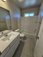 Full bath featuring shower / tub combination, toilet, vanity, a textured ceiling, and tile patterned floors