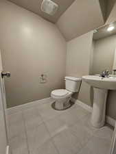 Bathroom featuring vaulted ceiling, toilet, baseboards, a sink, and a textured ceiling