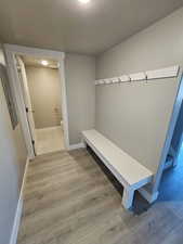 Mudroom featuring a textured ceiling, wood finished floors, baseboards, and electric panel