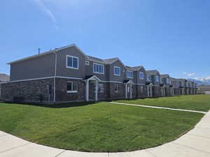 View of front facade with a front yard, brick siding, a residential view, stucco siding, and cooling unit