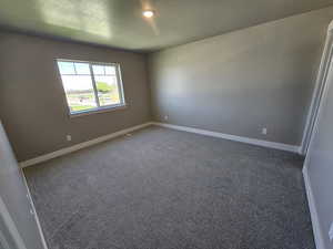 Unfurnished room with a textured ceiling, carpet floors, and baseboards