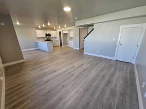 Unfurnished living room featuring light wood-type flooring and baseboards