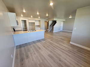 Kitchen with white cabinetry, a peninsula, baseboards, a sink, and light countertops
