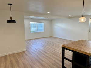 Unfurnished living room featuring light wood-style floors, baseboards, recessed lighting, and a textured ceiling