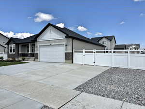 View of side of home featuring an attached garage, fence, board and batten siding, a gate, and concrete driveway