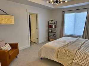 Bedroom featuring a chandelier, light carpet, and baseboards