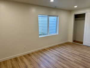 Unfurnished bedroom with wood finished floors, recessed lighting, baseboards, and a closet