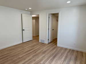 Unfurnished bedroom with recessed lighting, light wood-type flooring, baseboards, and a walk in closet