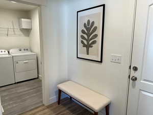 Laundry room with washing machine and dryer, light wood-type flooring, and baseboards