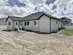 Back of property with fence, stucco siding, and a shingled roof