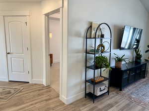 Corridor with light wood-type flooring and baseboards