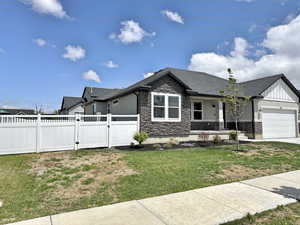 View of front of home featuring stone siding, a gate, a garage, board and batten siding, and concrete driveway