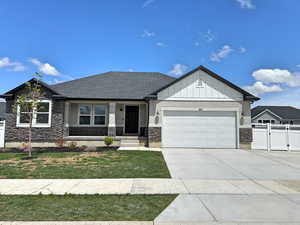 View of front of house featuring a gate, a garage, driveway, board and batten siding, and stone siding